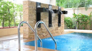 Piscina con pared de piedra y escaleras de metal.
