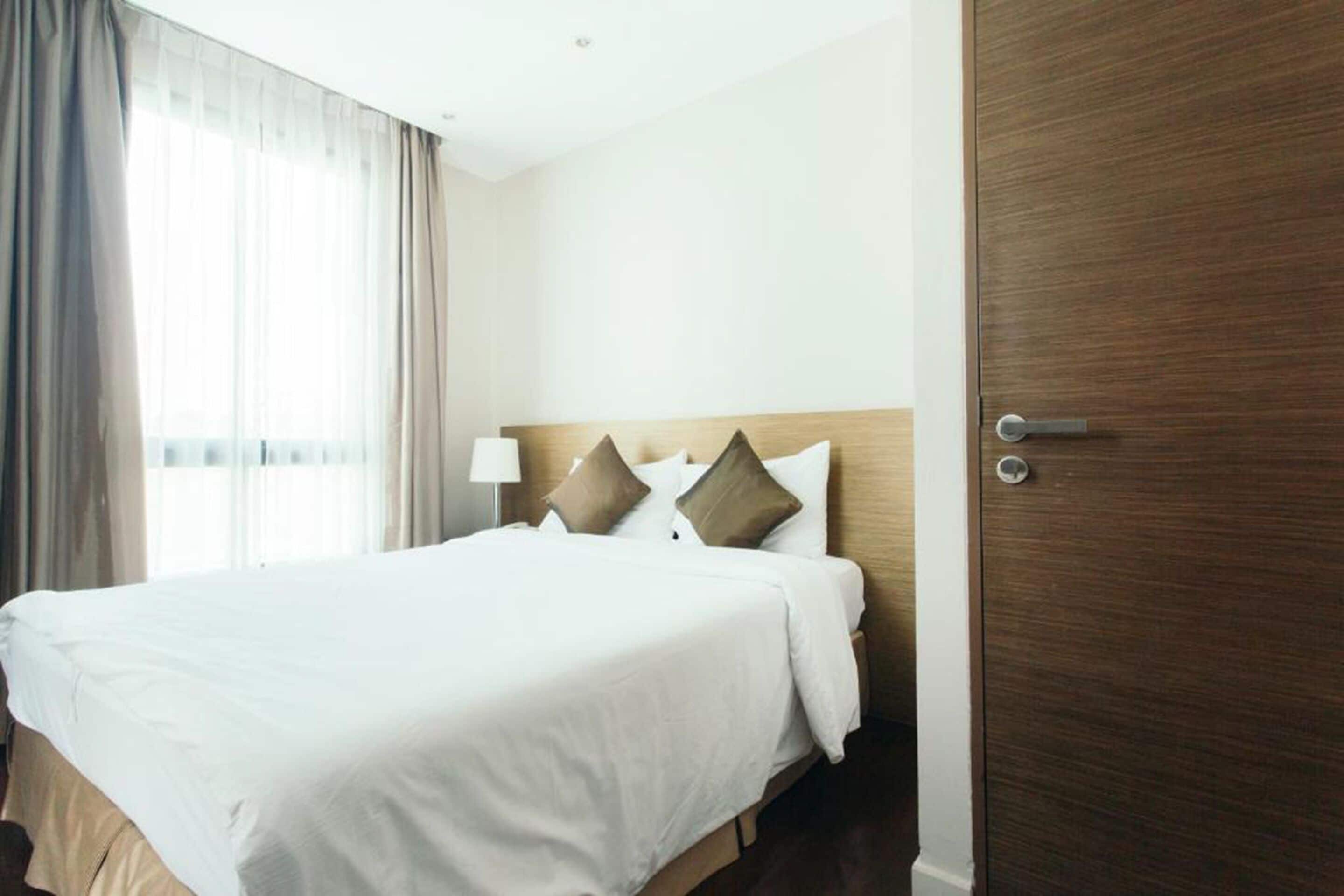A hotel room with a large bed, a wooden headboard, and a door with a handle.