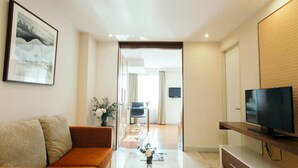Una sala de estar moderna con un sofá, un televisor sobre un mueble de madera y un cuadro en la pared.