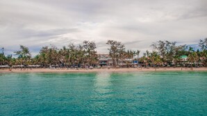 A beach with clear turquoise water, palm trees, and beach umbrellas. - Boracay Uptown (Boracay Island)