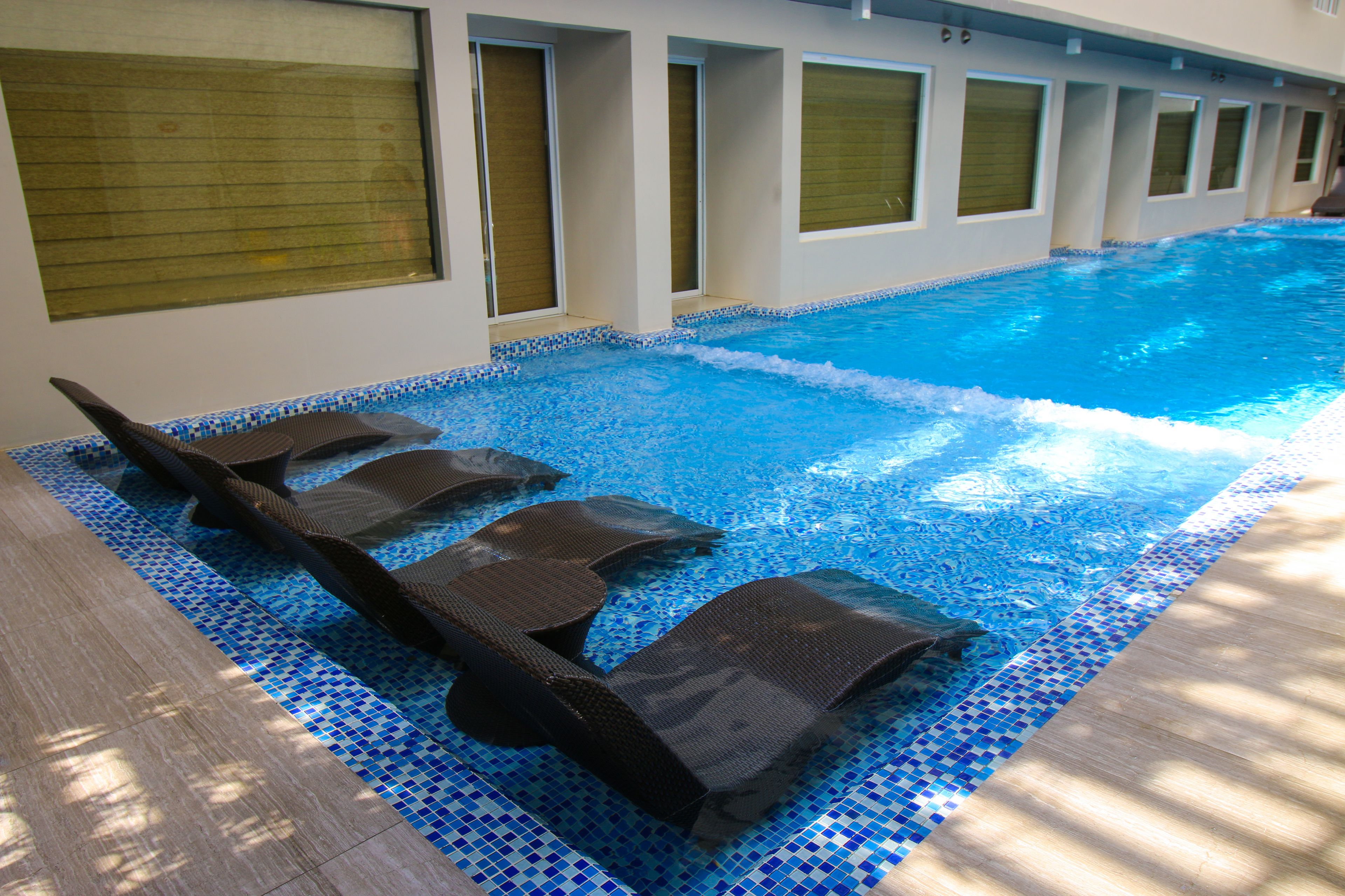 A swimming pool with lounge chairs and a tiled border.
