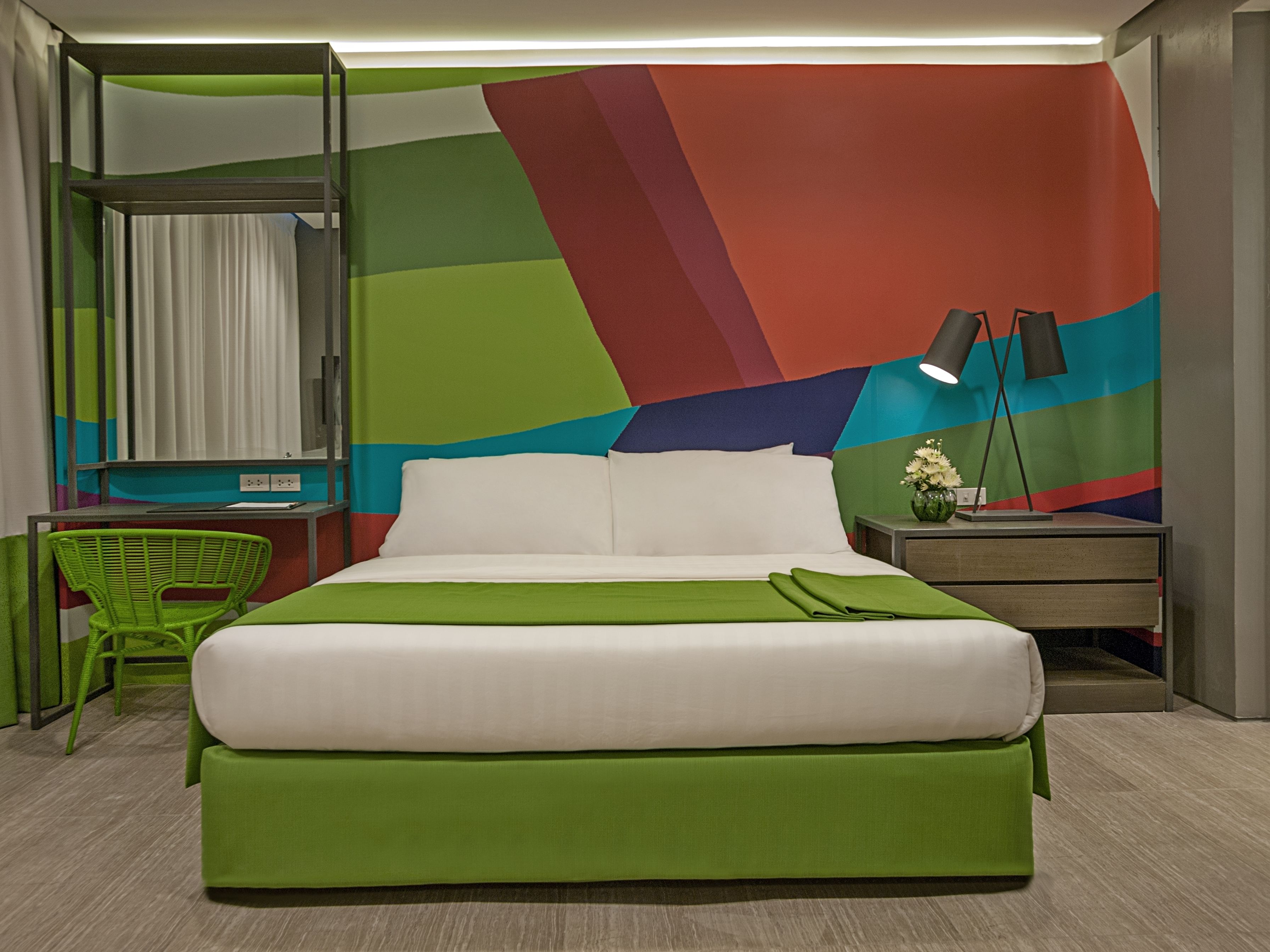 A modern hotel room with a large bed, a desk, and a chair.