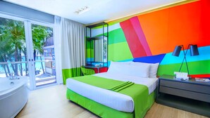 A modern hotel room with a large bed, a desk, and a view of palm trees through the glass door. - Boracay Uptown (Boracay Island)