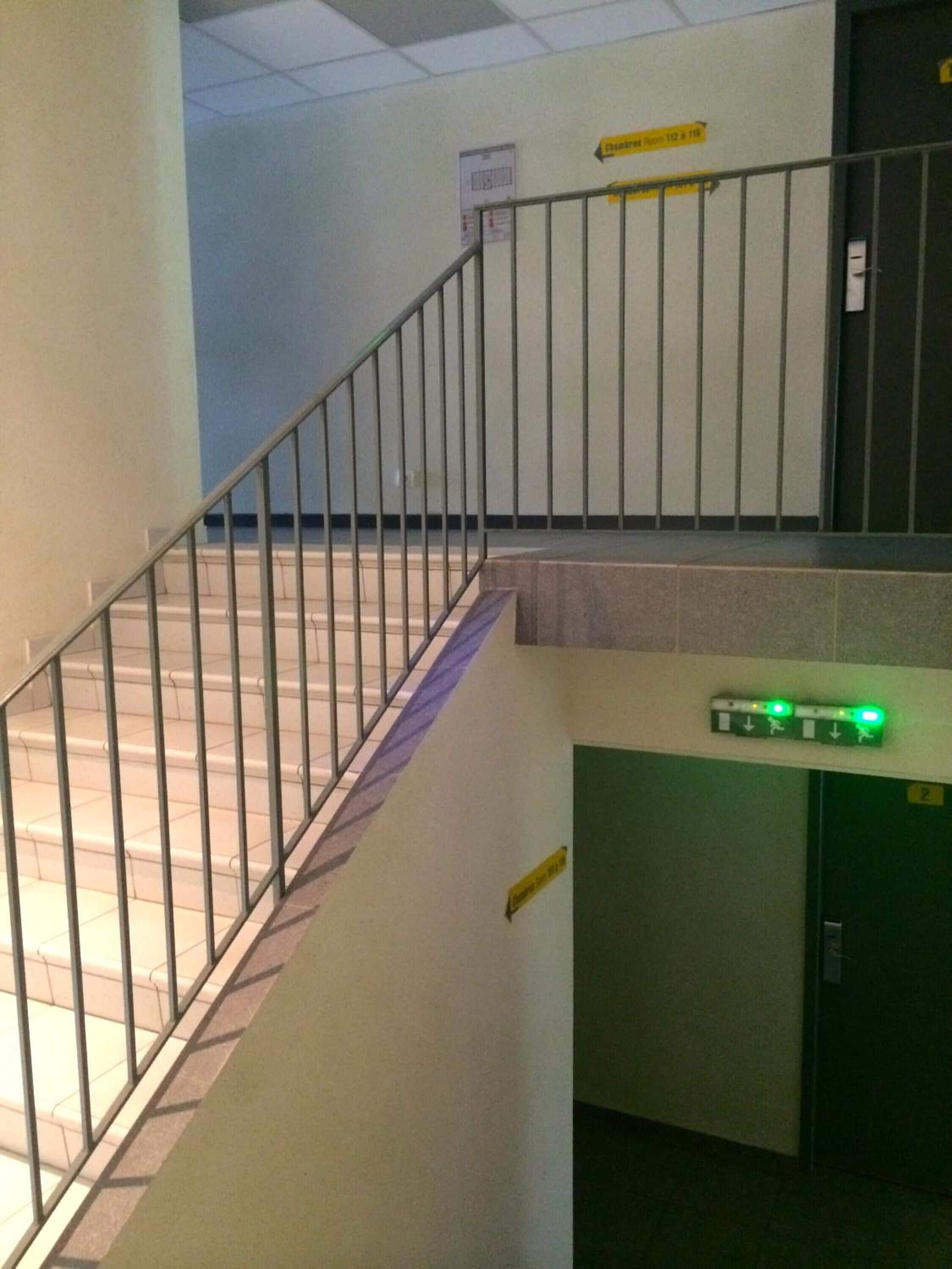 A staircase with metal railings leading to an elevator.
