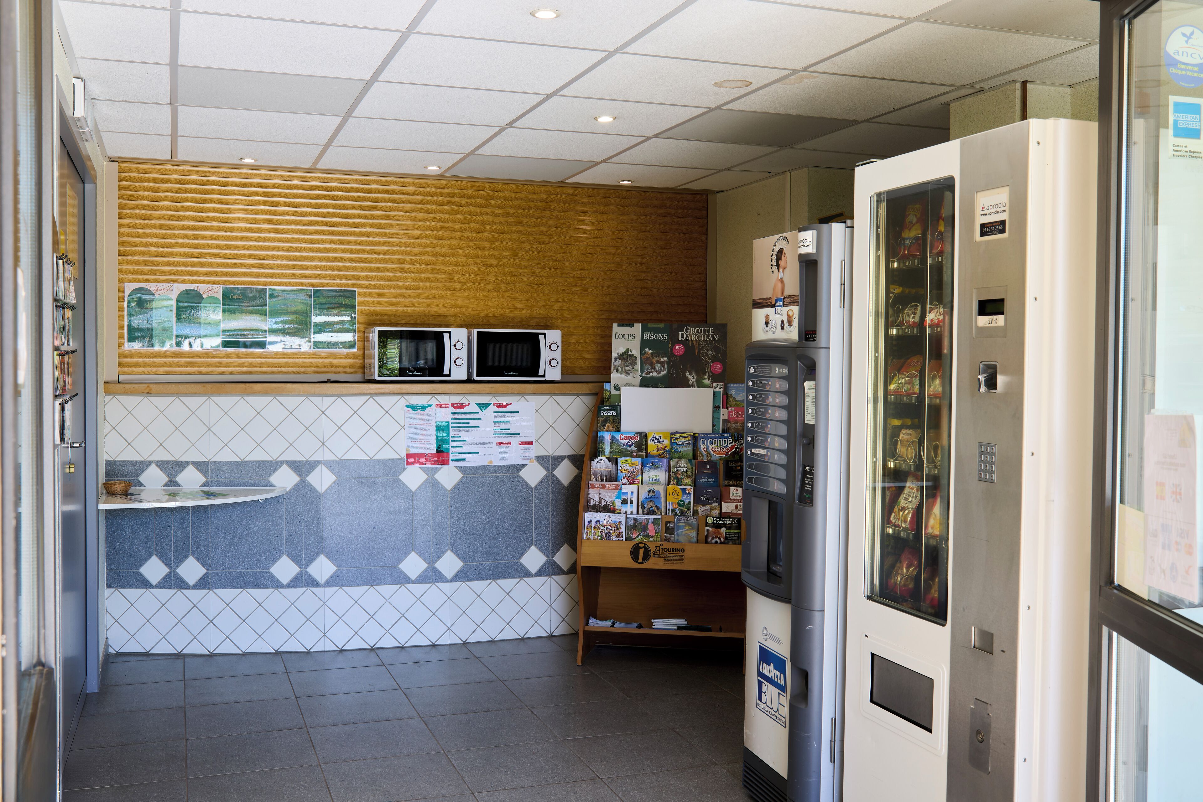 Una cocina equipada con microondas, refrigerador y máquina expendedora.