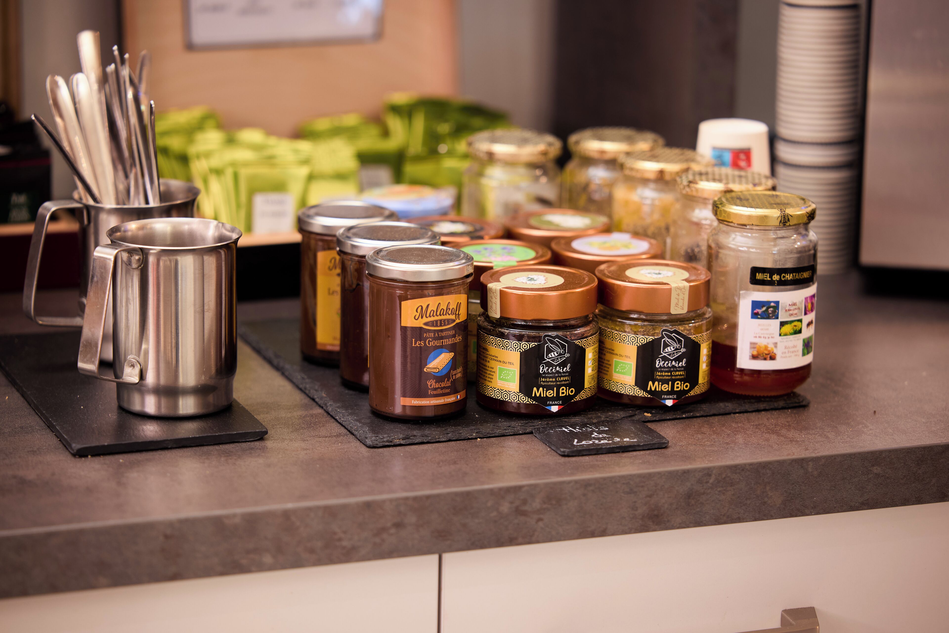 A variety of food items, including jars of honey and other condiments, on a counter.
