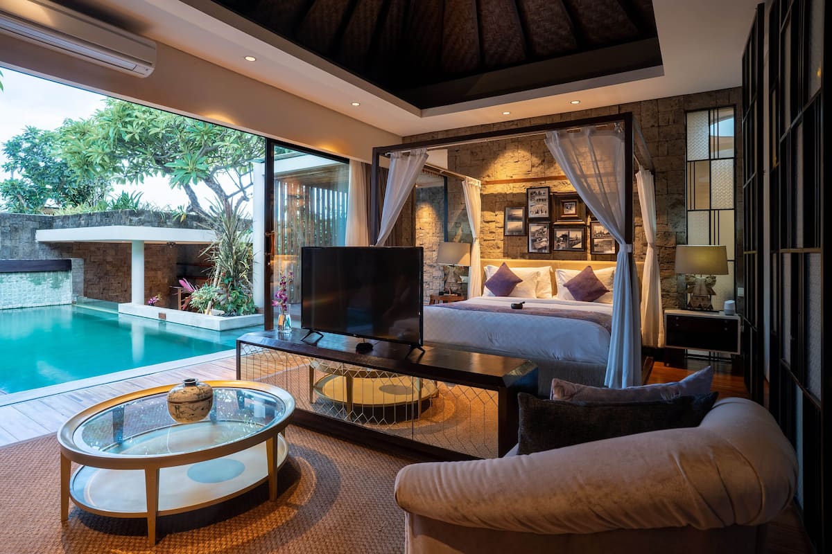 A bedroom with a large bed, a TV, and a glass coffee table.