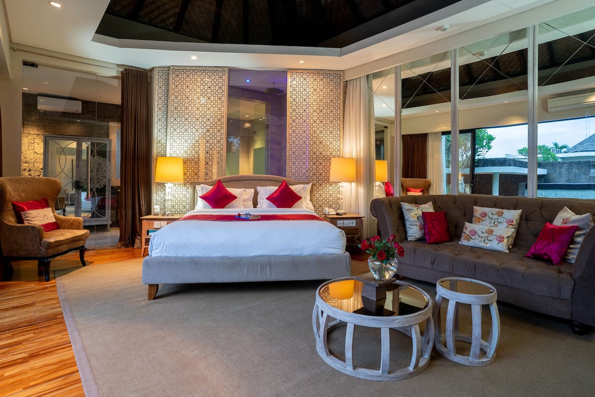 A spacious bedroom with a large bed, a sofa, and two side tables.