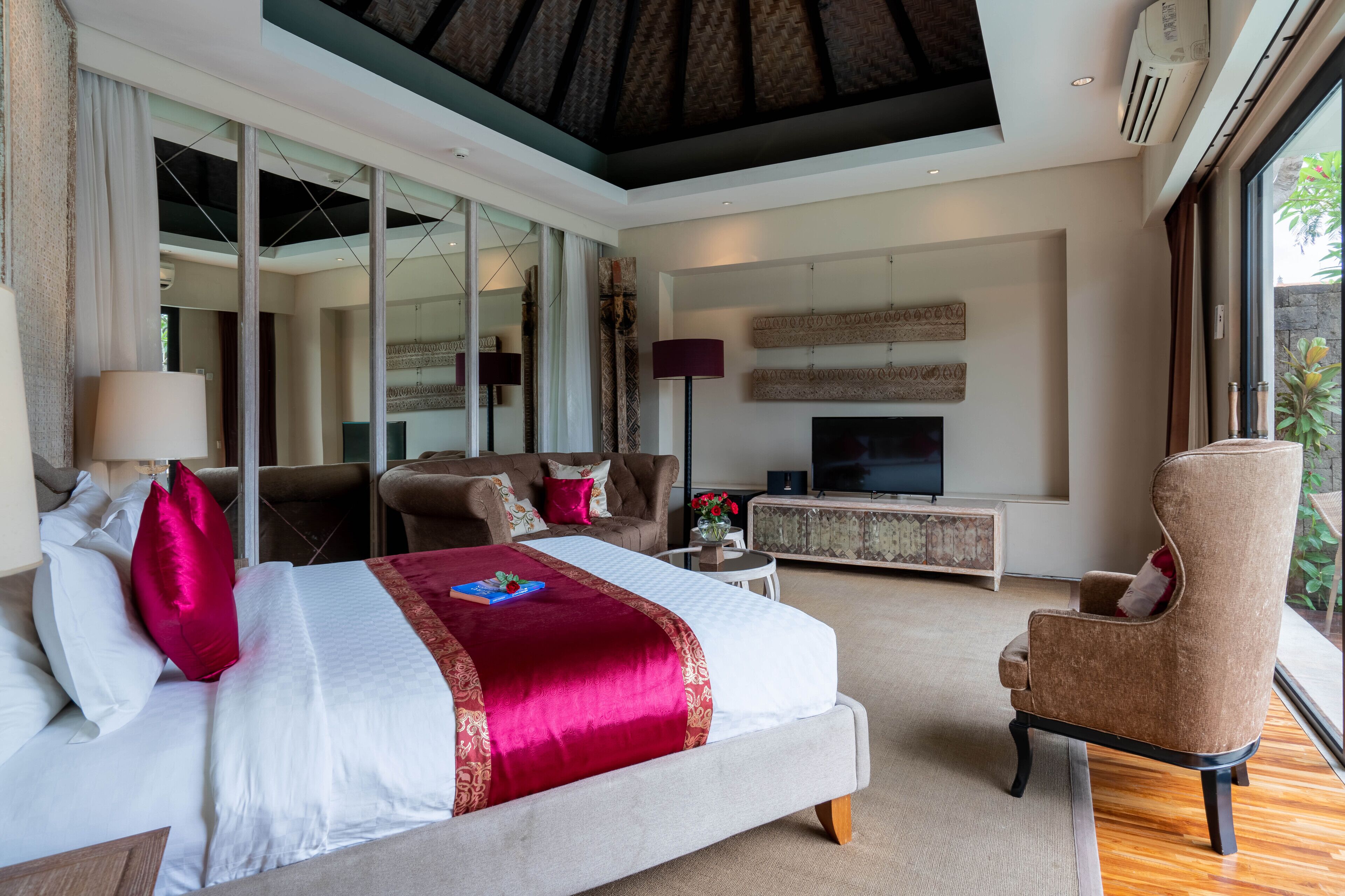 A modern bedroom with a large bed, a TV, and a seating area.