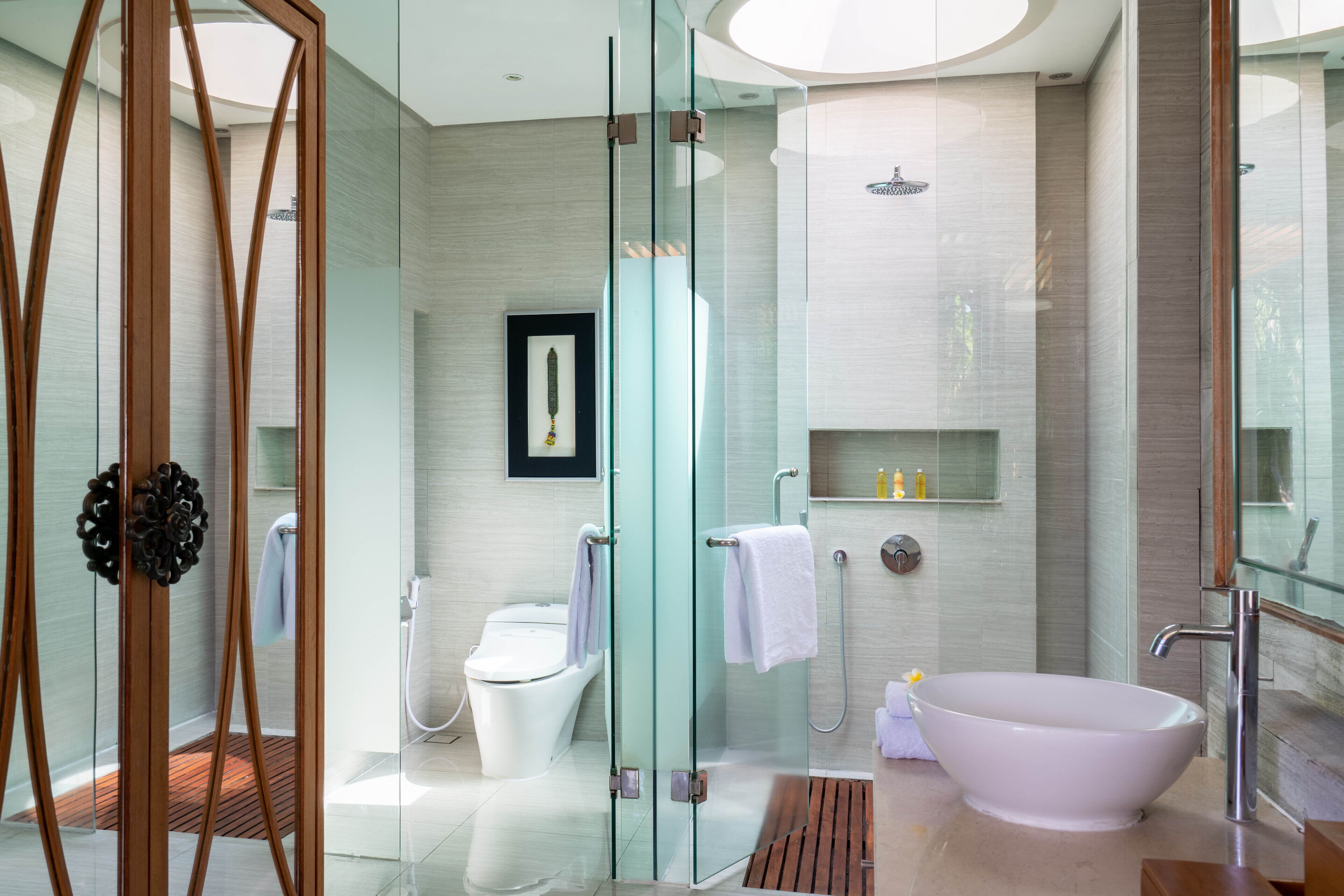 A modern bathroom with a glass-enclosed shower, a freestanding bathtub, and a toilet.