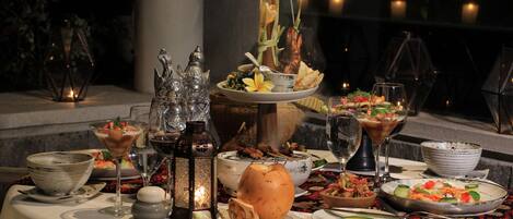 Mesa servida con diversos platos, vasos y objetos decorativos, evocando una experiencia gastronómica formal.
