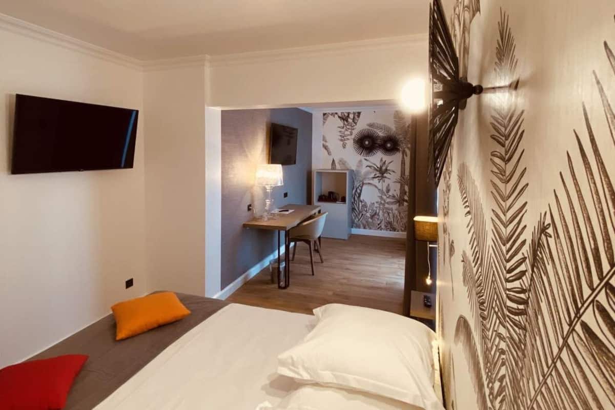 Hotellihuone, jossa on sänky, työpöytä ja seinälle asennettu televisio.