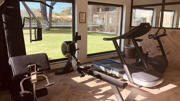 Un gimnasio en casa equipado con cinta de correr, bicicleta estática y máquina de remo.