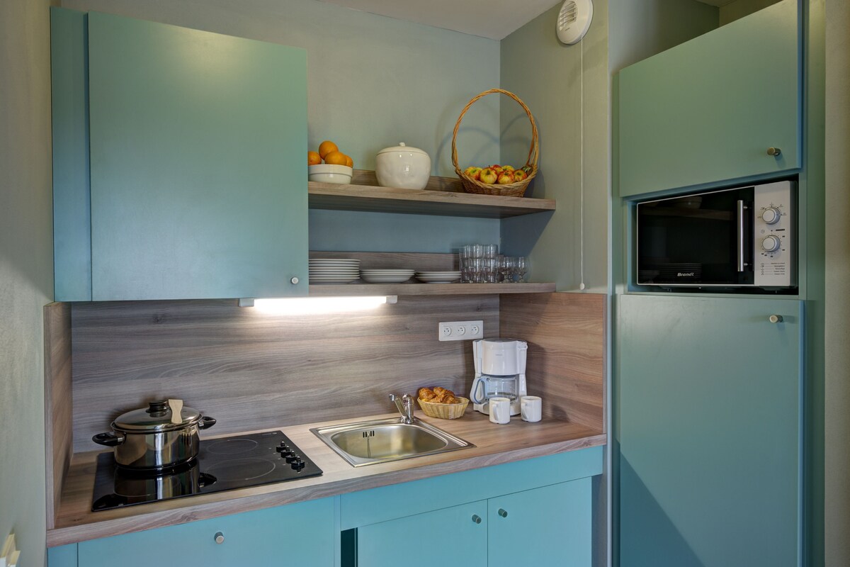 Una cocina compacta con microondas, cafetera y lavabo.