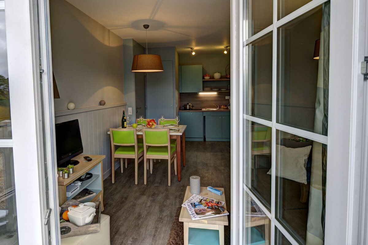 Un espacio habitable compacto con comedor, cocina y televisor.
