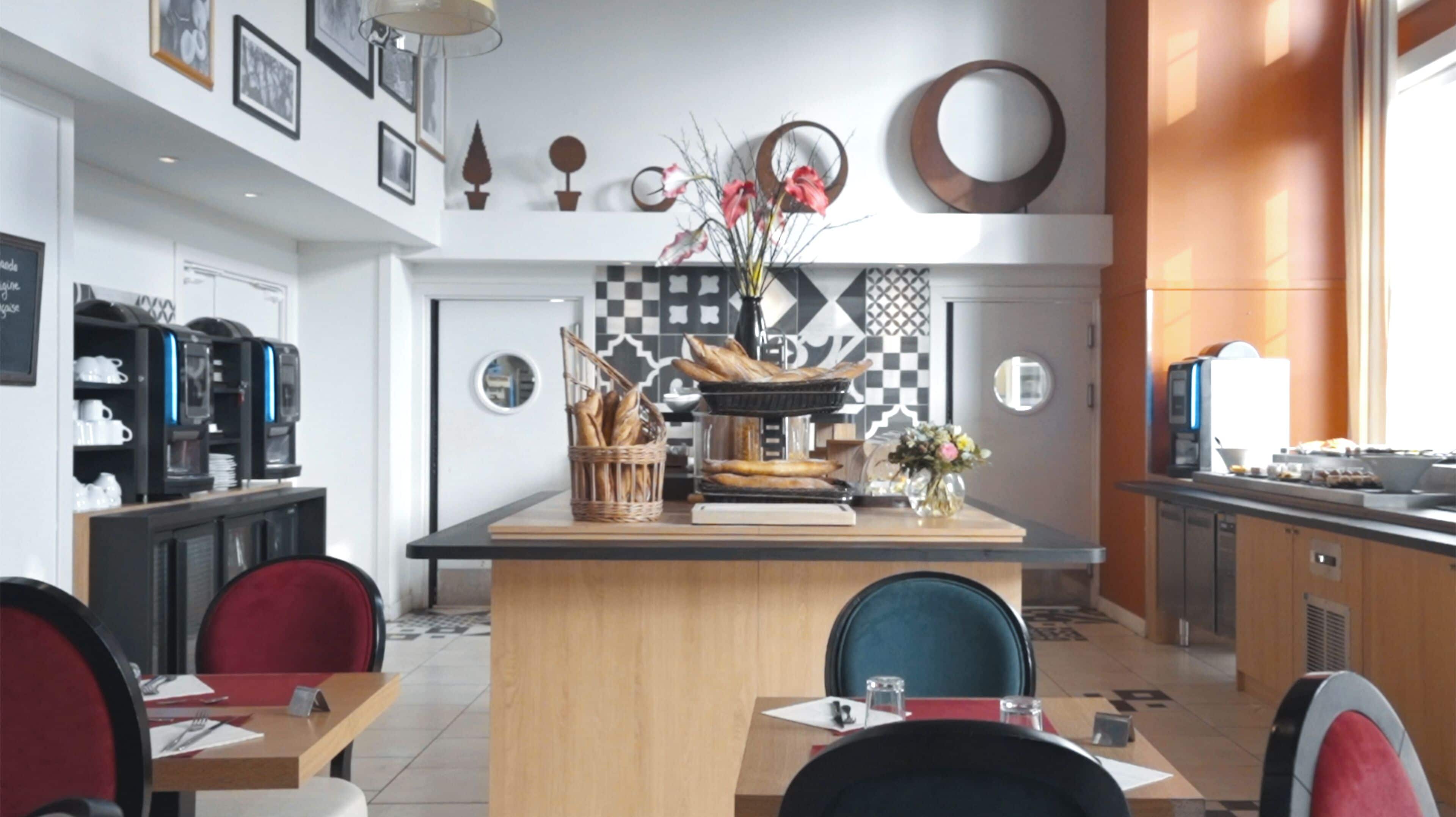 A modern dining area with a central island, red chairs, and a coffee machine.
