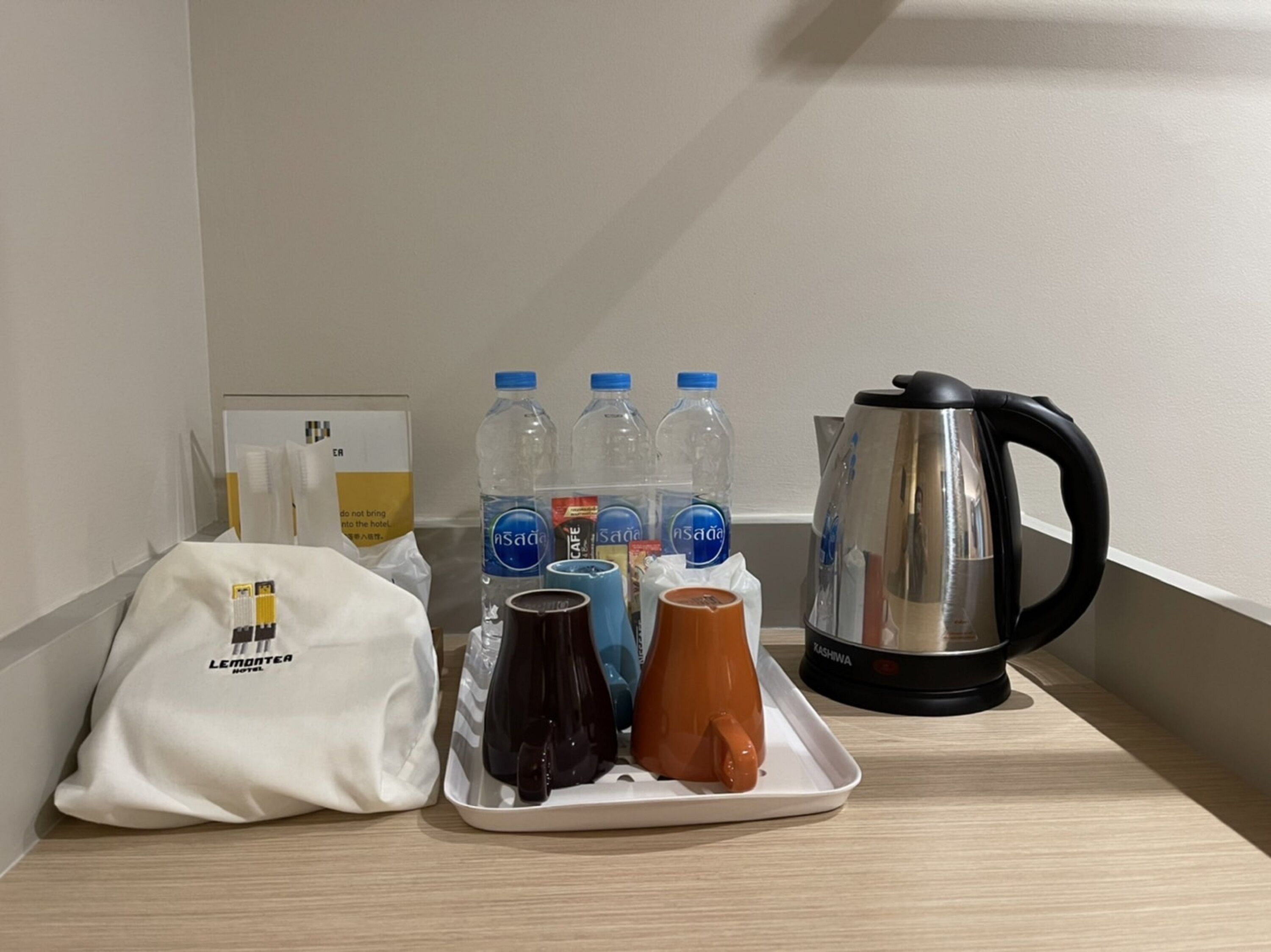 Un plateau avec des bouteilles d’eau, une cafetière et une tasse sur le comptoir d’un hôtel.