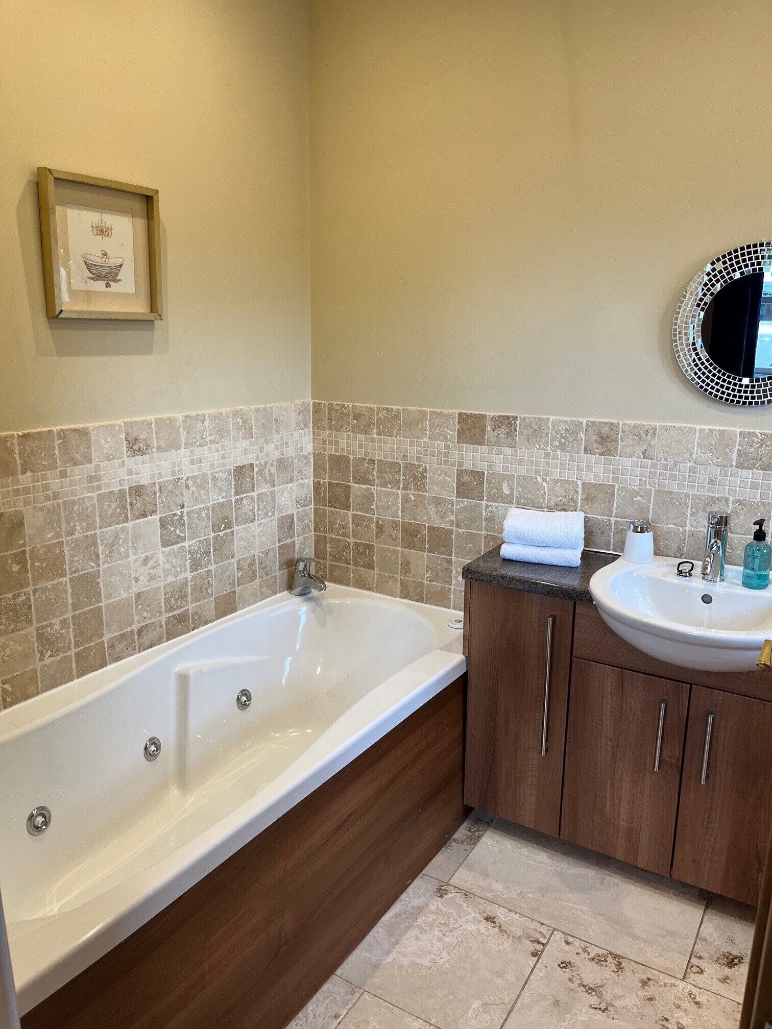 A bathroom with a large bathtub, a sink, and a mirror.