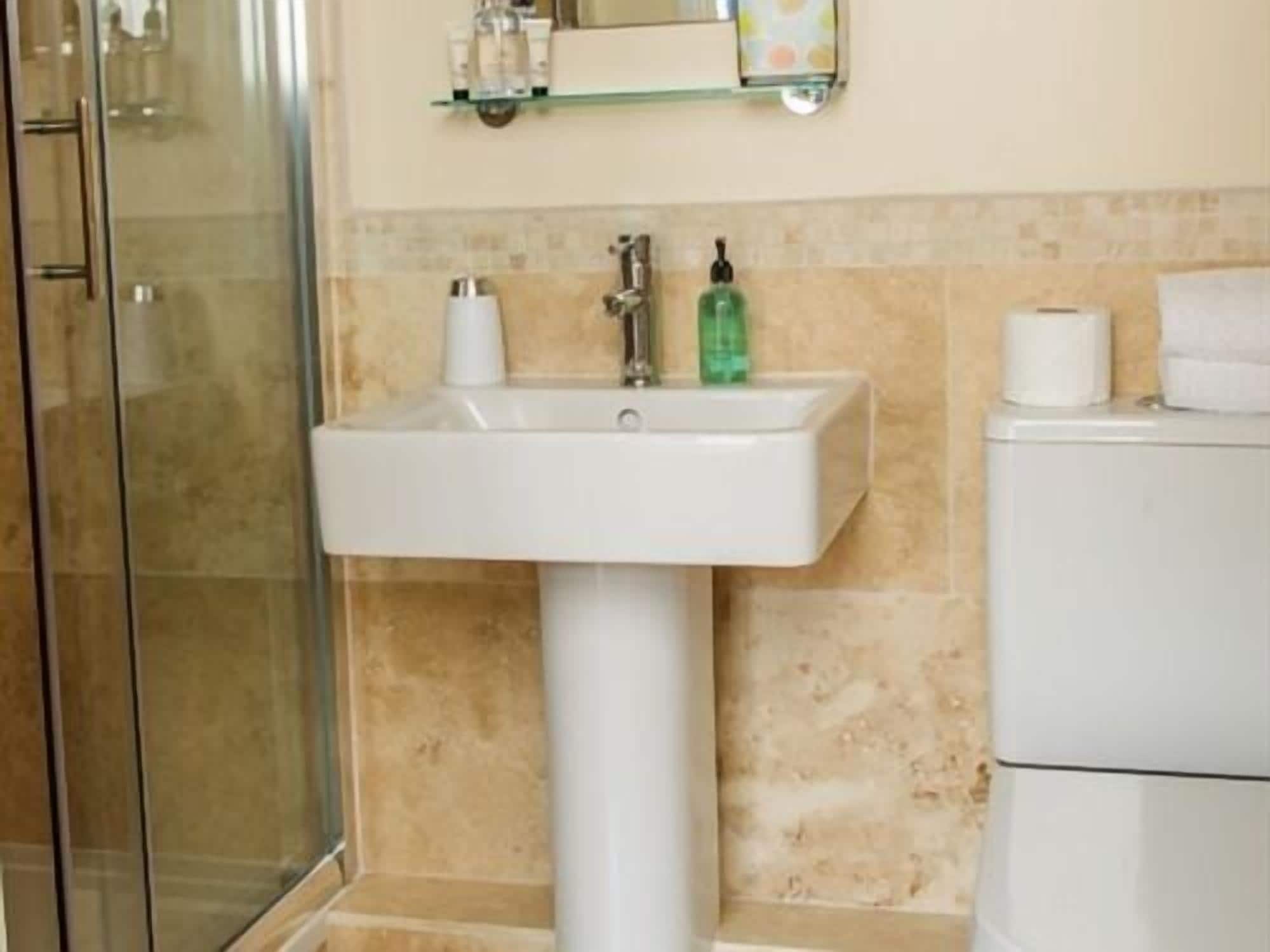 A bathroom with a white sink, a glass shower enclosure, and a toilet.