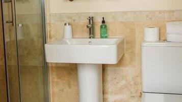 A bathroom with a white sink, a glass shower enclosure, and a toilet.