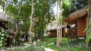 A pathway leading to thatched-roof huts surrounded by lush greenery. - Gecko Lipe Resort (Koh Lipe)
