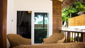 A wicker chair and table set on a balcony with a view of greenery. - Gecko Lipe Resort (Koh Lipe)