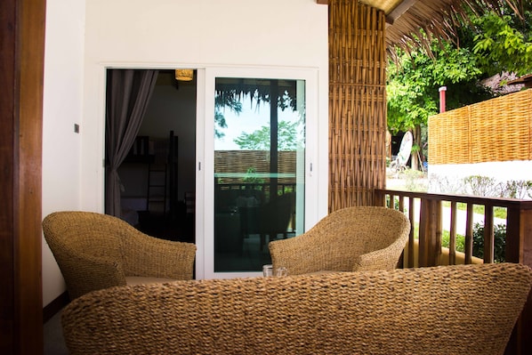 Un conjunto de sillón y mesa de mimbre en un balcón con vista a follaje.