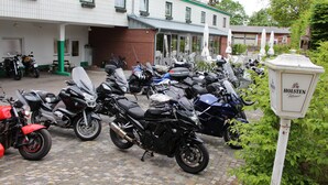 Varias motocicletas estacionadas frente a un edificio con toldo verde y un letrero que dice 'HOLSTEN Pilsener'.