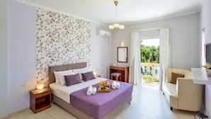 A bedroom with a bed, bedside tables, a desk, a chair, and a balcony with a view. - Poseidon Apartments (Chania)