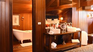 A wooden bathroom with a bathtub, a vanity with a mirror, and a towel rack. - Villa Casato Residenza Boutique (Campos do Jordão)