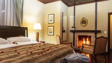 A hotel room with a bed, a fireplace, a chair, and a mirror on the wall.
