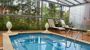 A swimming pool with clear blue water, surrounded by a wooden deck and lounge chairs. - Villa Casato Residenza Boutique (Campos do Jordão)