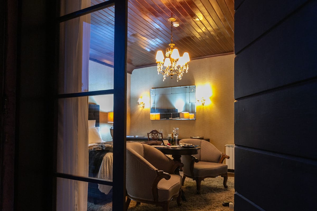 Una habitación acogedora con techo de madera, un candelabro y un comedor con sillas y una mesa.