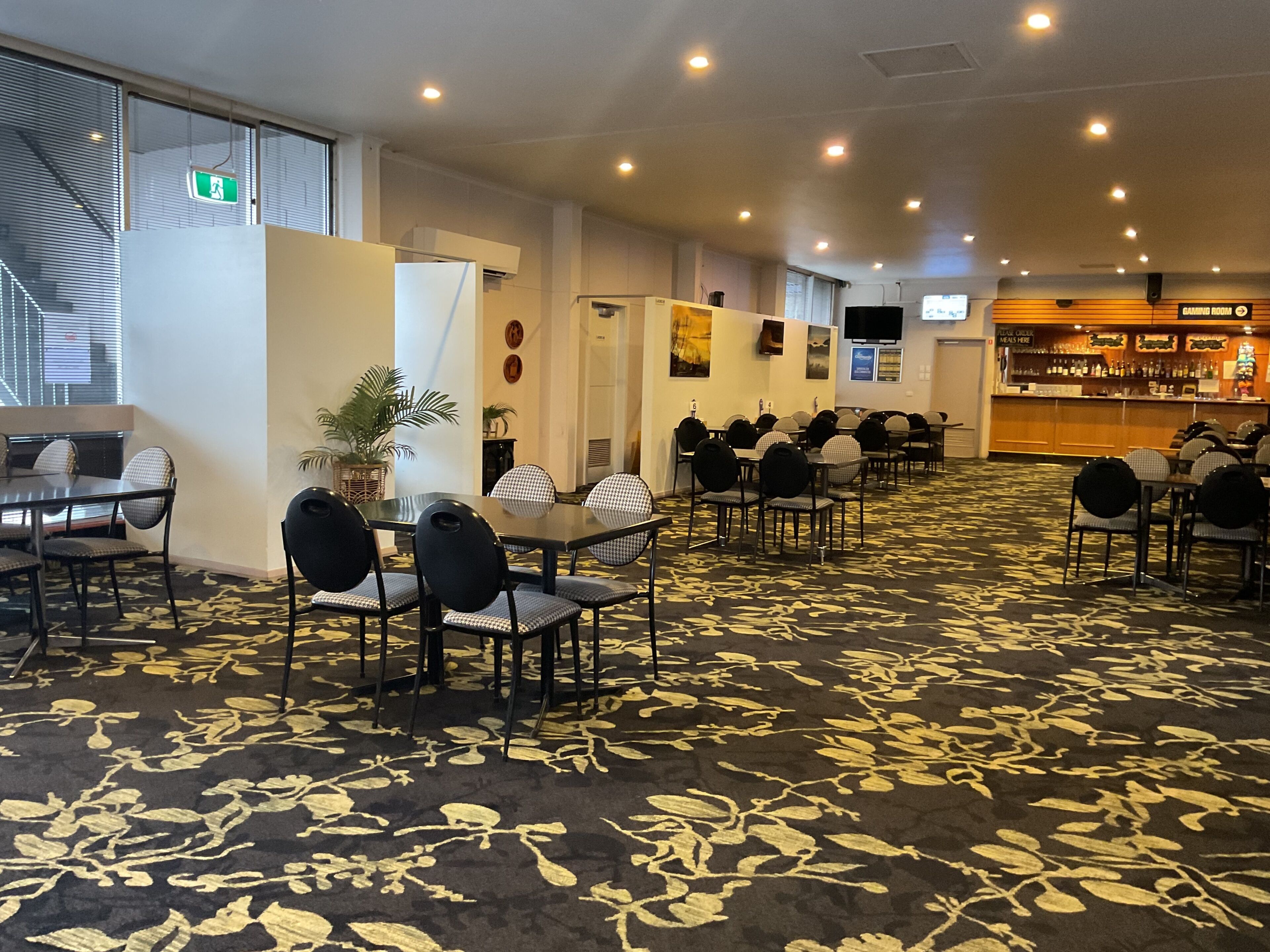 Een hotelconferentieruimte met tafels, stoelen, een bar en een kamerbreed tapijt met patroon.