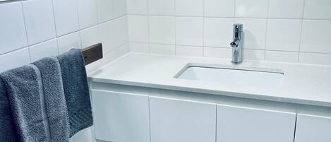A bathroom with a white sink, a towel rack with a towel, and a blue-tiled floor.