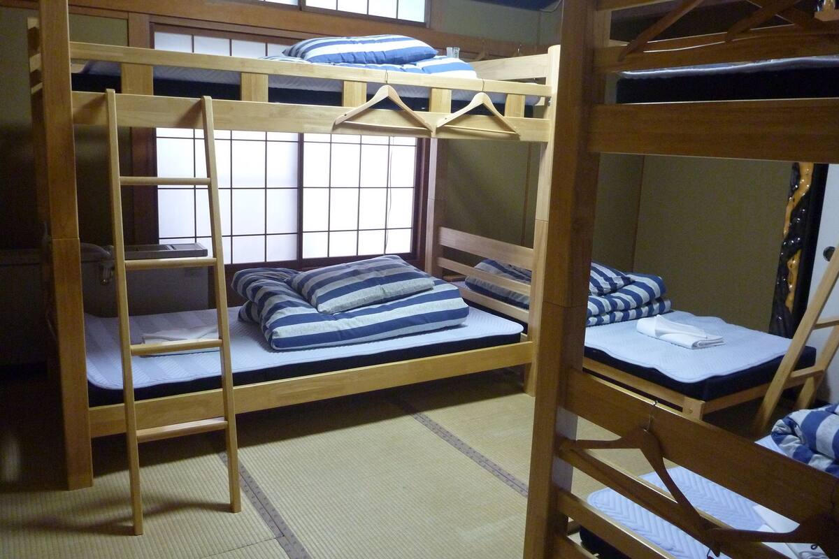 A bunk bed room with a wooden ladder, a hanging rack, and a window with a grid pattern.