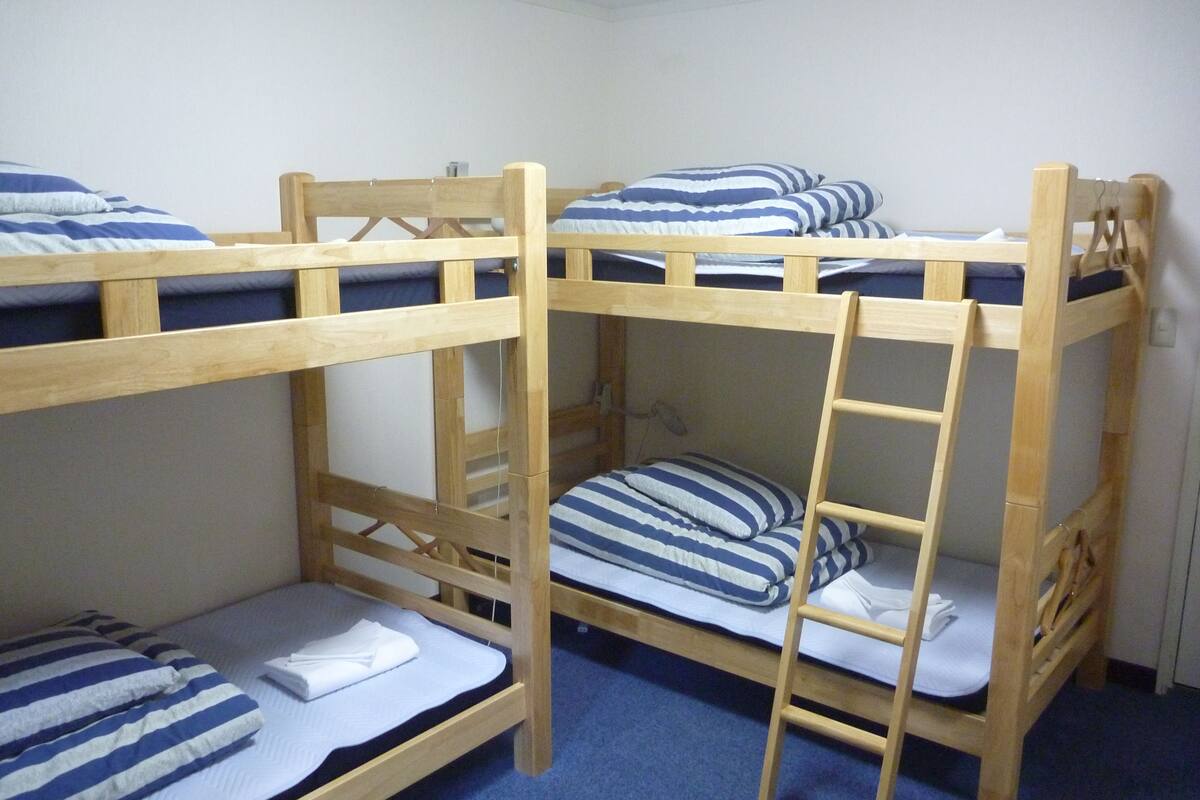 A bunk bed room with two beds, each with blue and white striped bedding.
