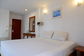 A hotel room with a large bed, a bedside table, a mirror, a wall-mounted light, and a framed picture. - 18 Coins Budget Hotel (Pattaya)