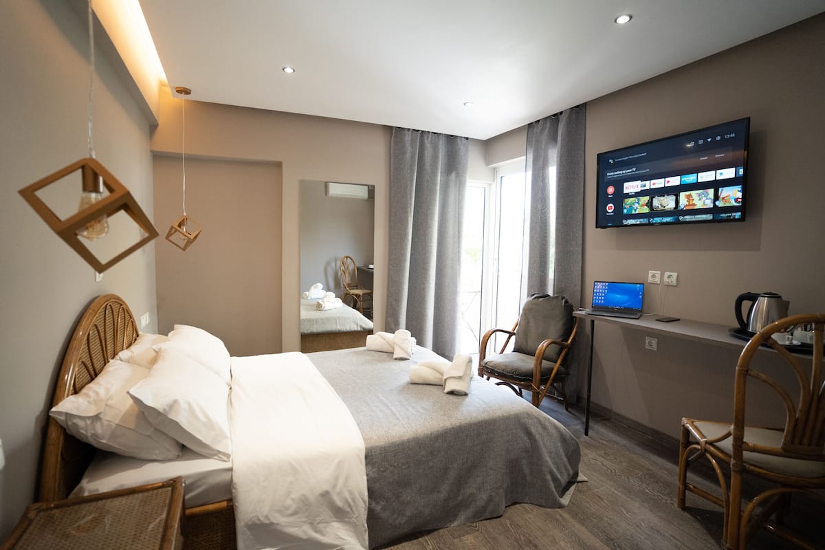 A hotel room with a bed, a desk with a laptop, a television, and a chair.