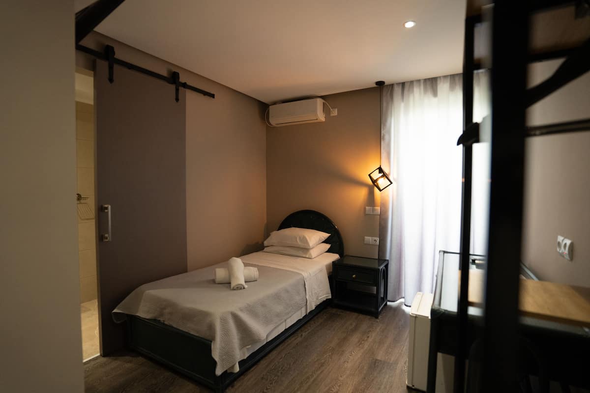 A bedroom with a bed, bedside table, and an air conditioning unit.