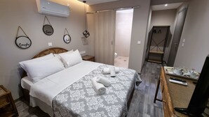 A hotel room with a bed, a TV, a bathroom, and a shower area.