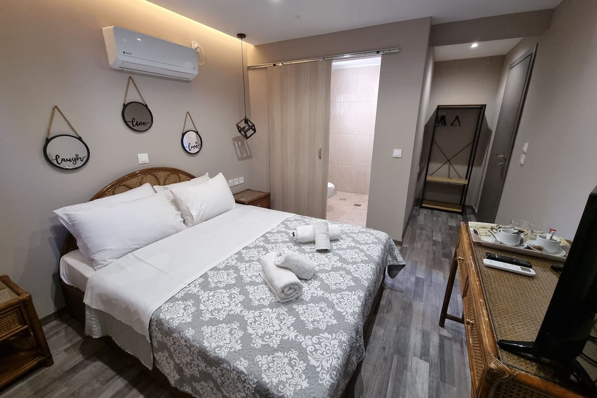 A hotel room with a bed, a TV, a bathroom, and a shower area.