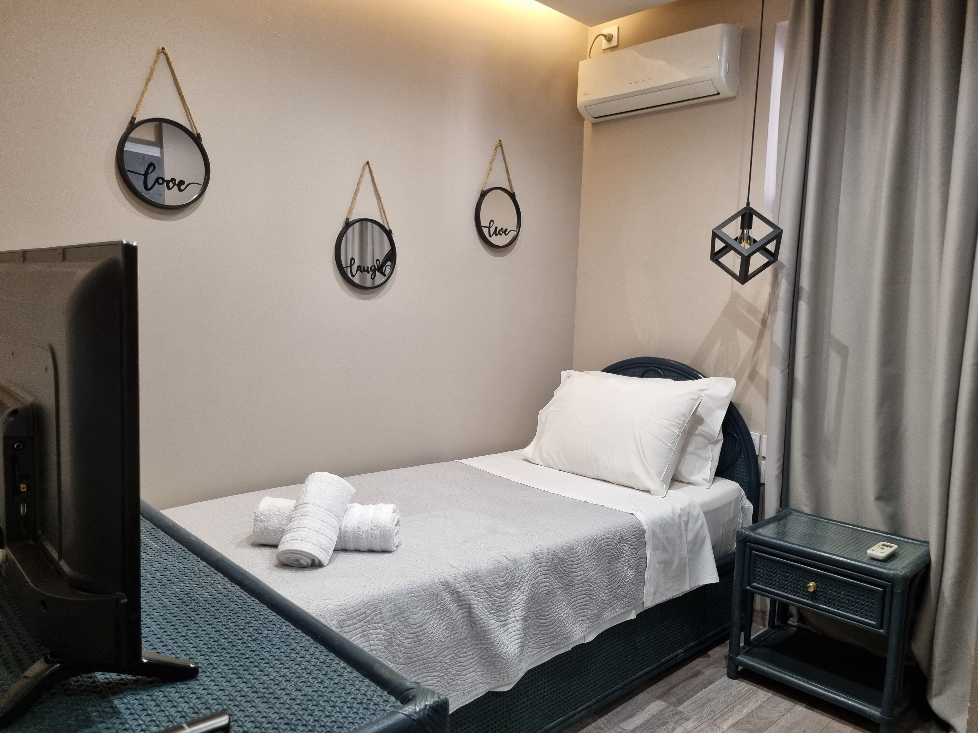 A neatly arranged bedroom with a bed, a TV, and a small bedside table.