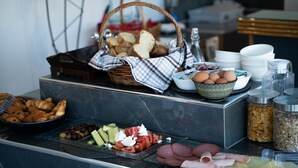 A buffet table with various food items including bread, eggs, olives, and meats.