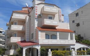 A multi-story hotel with a red-tiled roof, balconies, and a sign indicating it is a hotel. - Parthenis Riviera Hotel (Vari-Voula-Vouliagmeni)