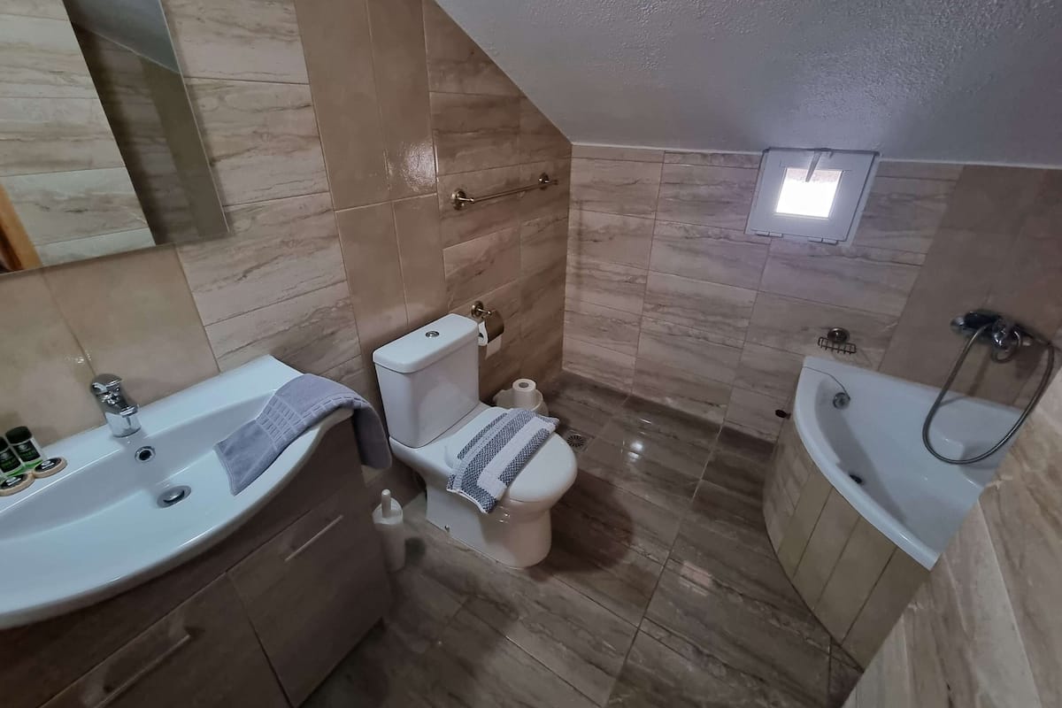 A modern bathroom with a toilet, sink, and bathtub.