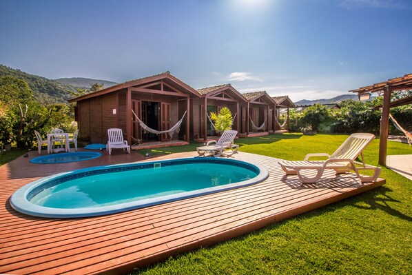Una piscina al aire libre, sillones reclinables de piscina