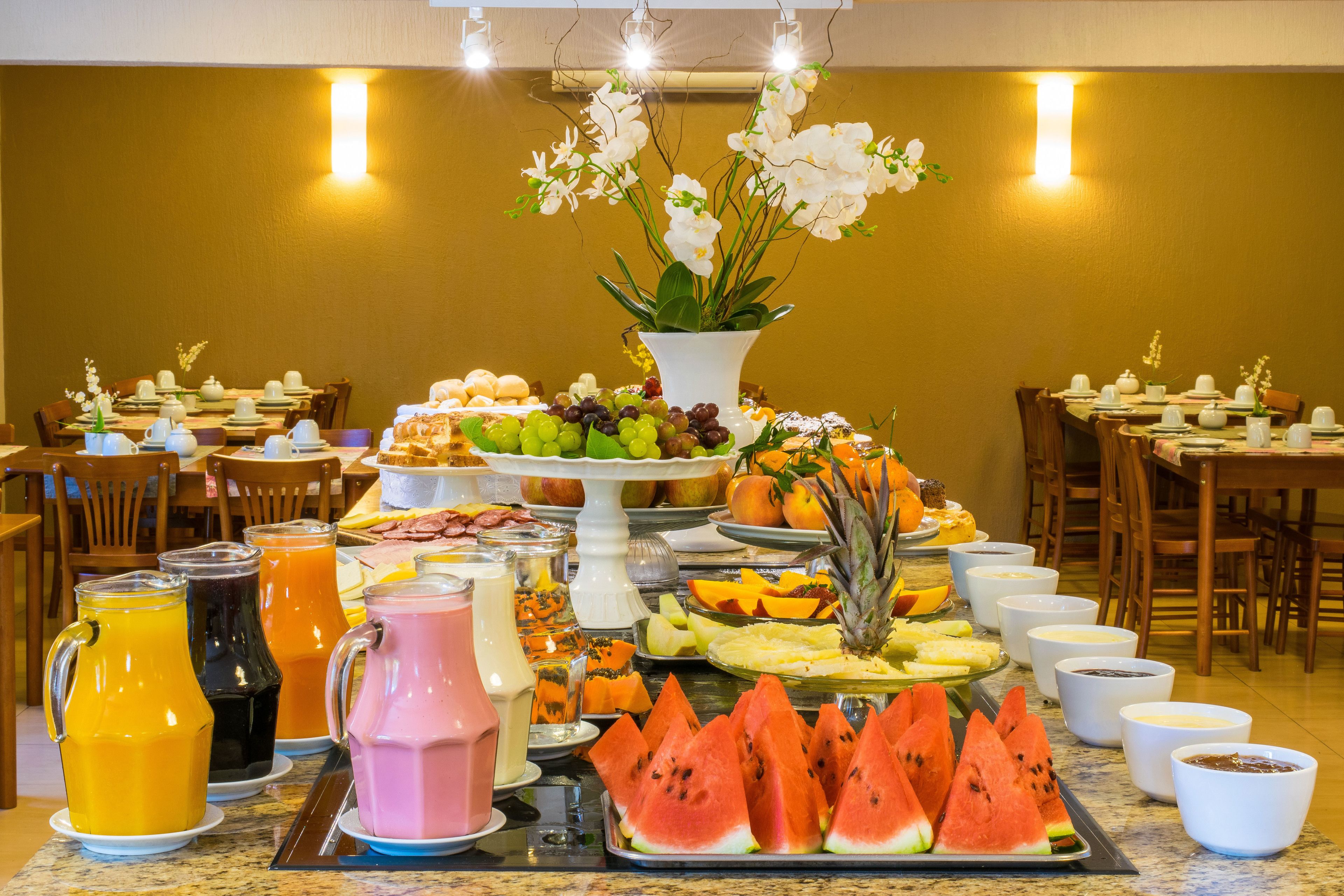 A buffet with various fruits, pastries, and beverages.