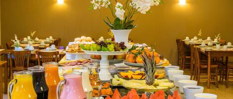 A buffet with various fruits, pastries, and beverages.