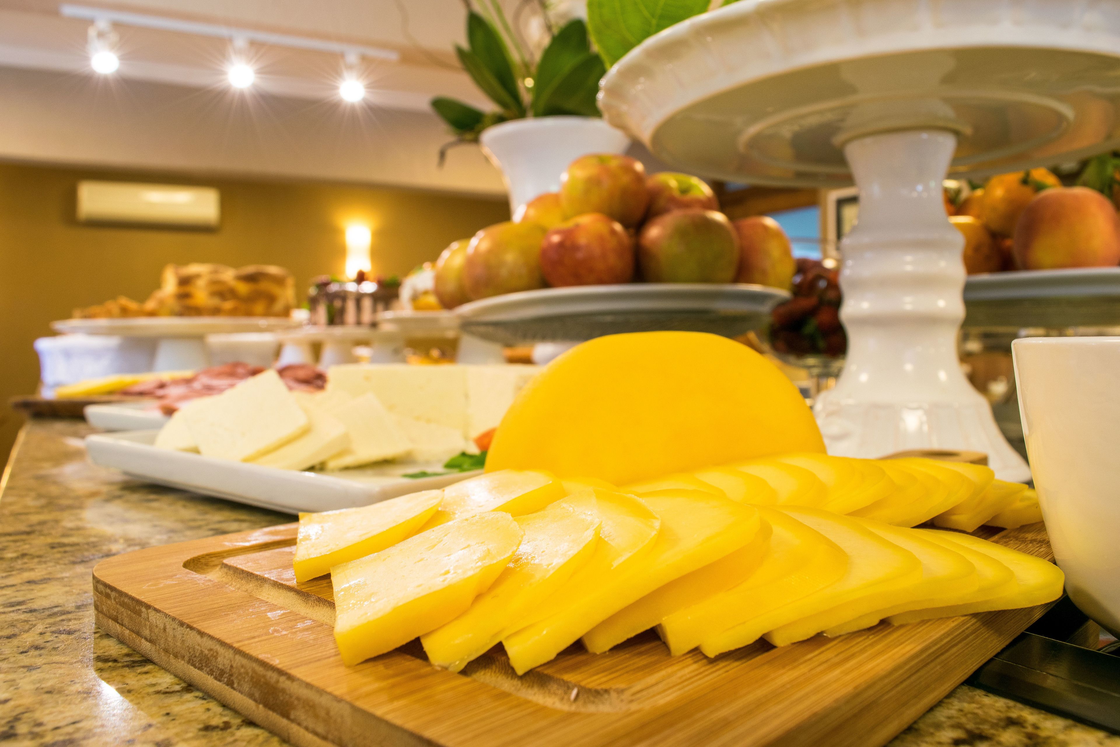 Un bufé con fruta amarilla en rodajas, queso y otros alimentos sobre una tabla de madera.